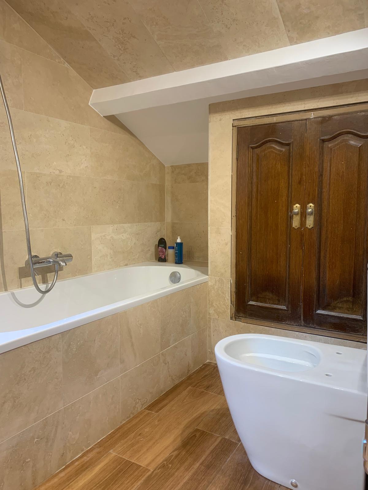 Baño con bañera exenta en Sant Cugat del Vallès: baño abuhardillado con bañera exenta y suelo efecto madera
