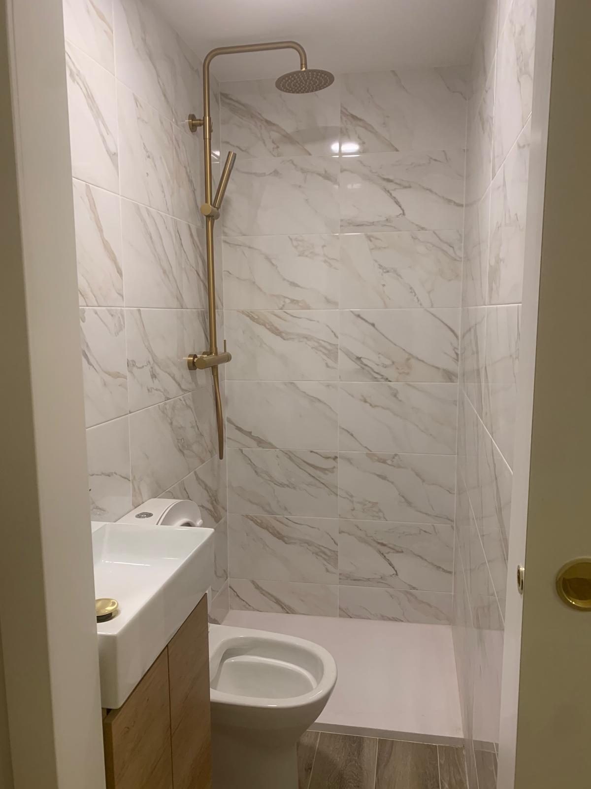 Reforma de baño en mármol con ducha y lavabo de diseño en Barcelona