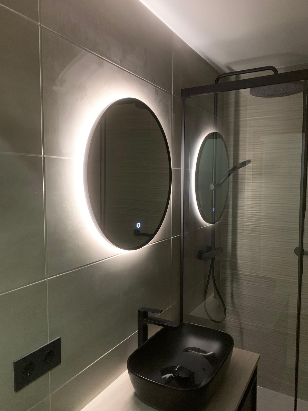 Reforma de baño en Poblenou, Barcelona: baño reformado con espejo LED retroiluminado, lavabo negro y ducha de obra
