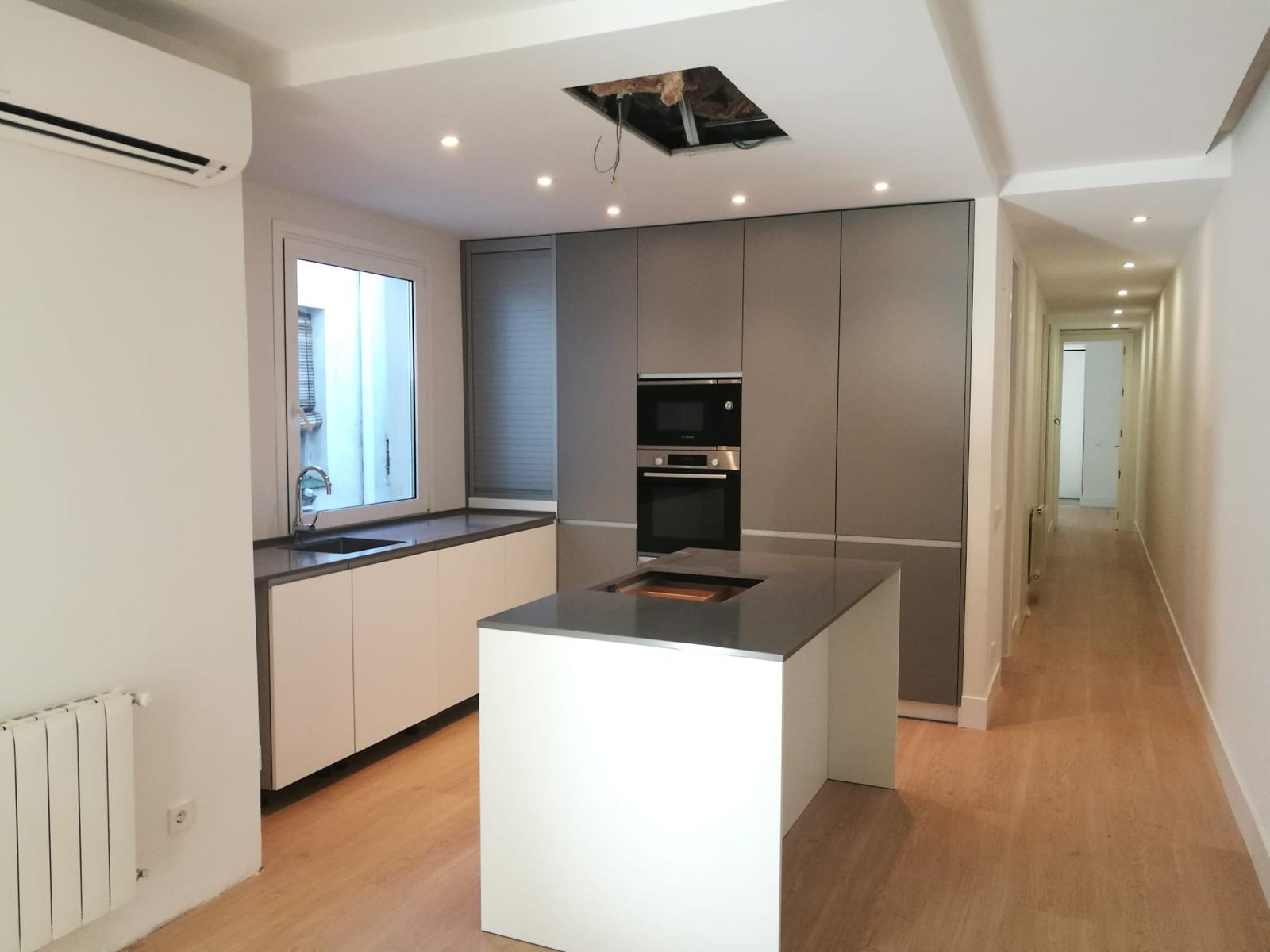 Reforma integral con cocina abierta e isla central — obra real de Grupo Vertikal